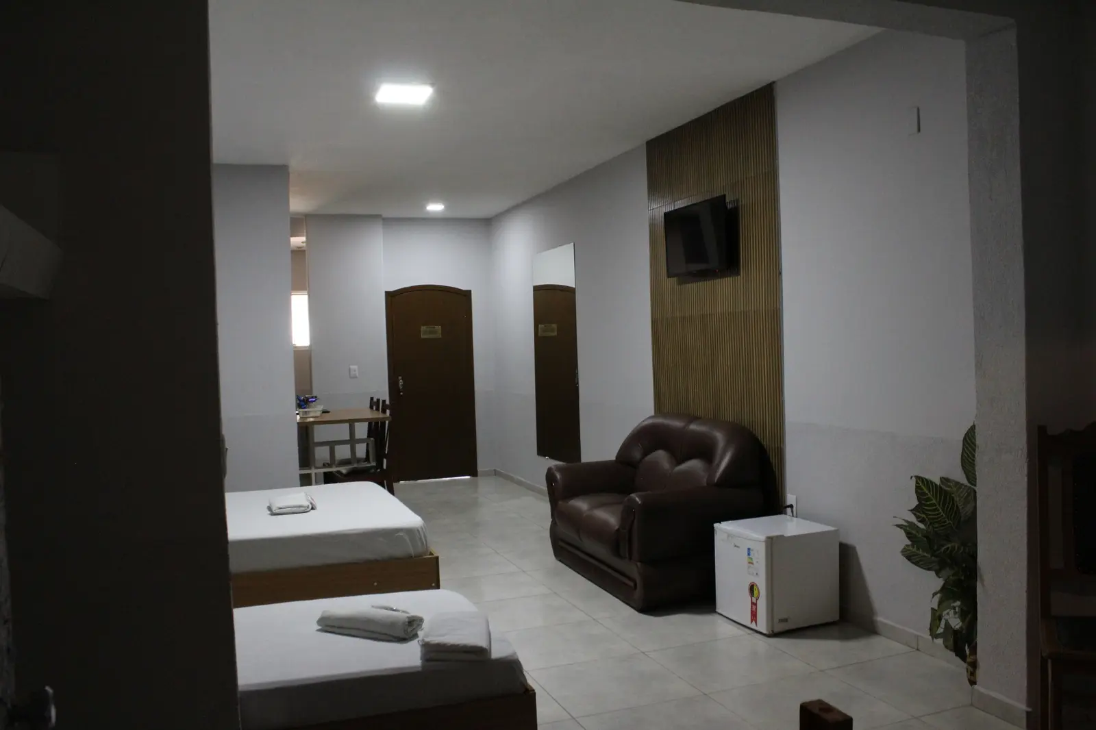 Suíte ampla com camas, sofá, TV e frigobar